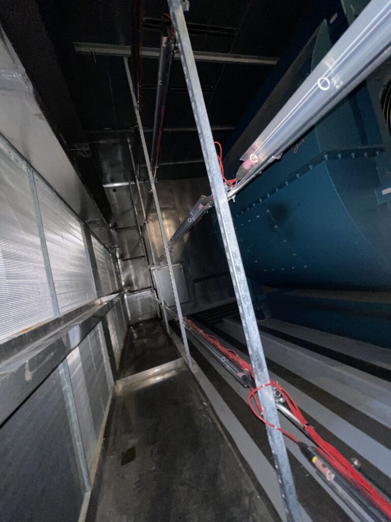 Figure 1: Multiple rows of UV light bars, supported by Unistrut, installed downstream of a cooling coil in a large capacity air handling unit. Courtesy: CDM Smith