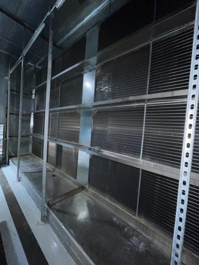 Figure 2: Multiple rows of bipolar ionization bars, supported on the upstream face of a cooling coil, in a large capacity air handling unit. Courtesy: CDM Smith