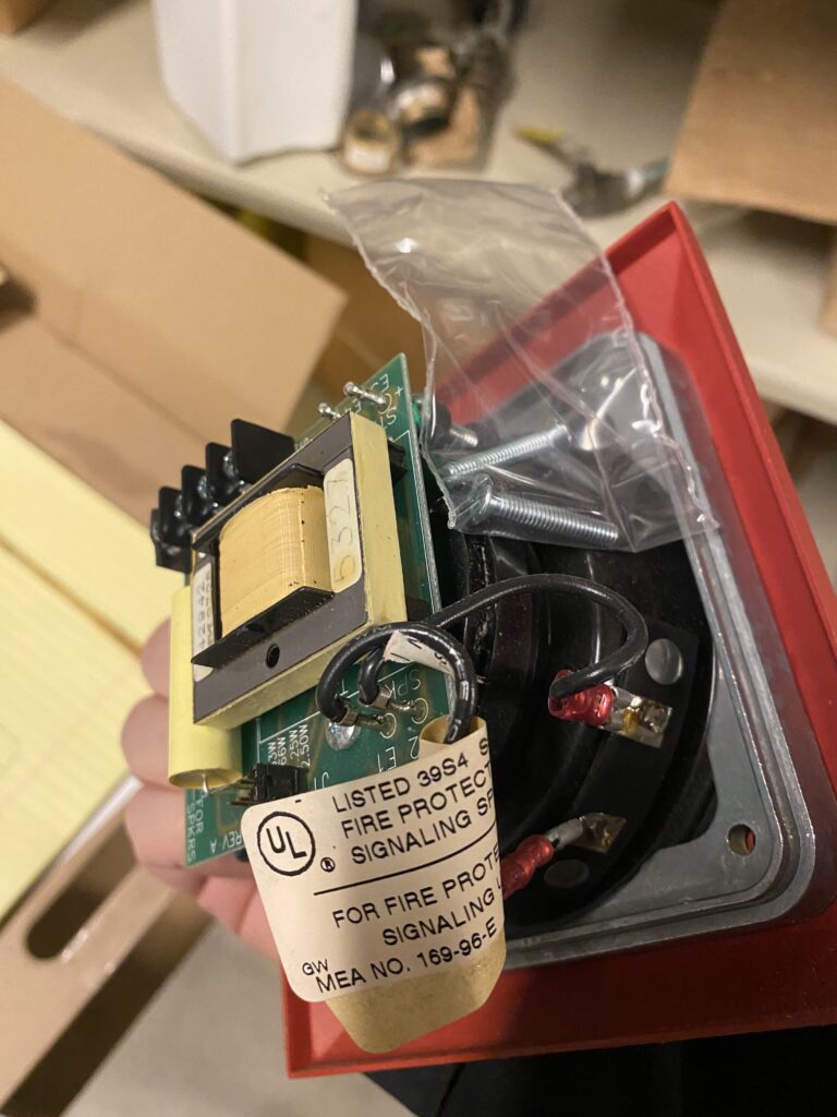 Backside of a fire alarm speaker showing a small 24/70 volt transformer and various wattage tap terminals to allow changes in sound levels. Excessive sound levels can impact voice intelligibility. Courtesy: McGuire Engineers Inc.