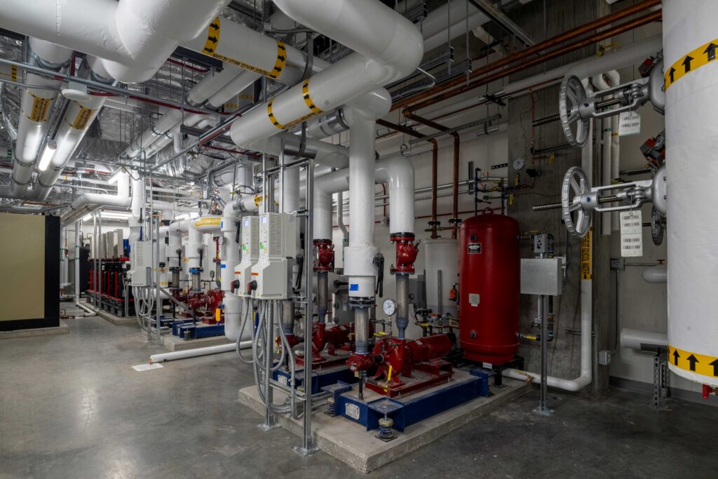 Figure 4: Medical College of Wisconsin Center for Cancer Discovery penthouse mechanical room showing (from left to right) the heat recovery chiller, condenser water pumps, plate-and-frame heat exchangers and preheat glycol water loop pumps. Courtesy: CannonDesign