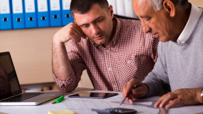 Senior and young architect working together on a project in the office, senior architect mentoring young colleague.
