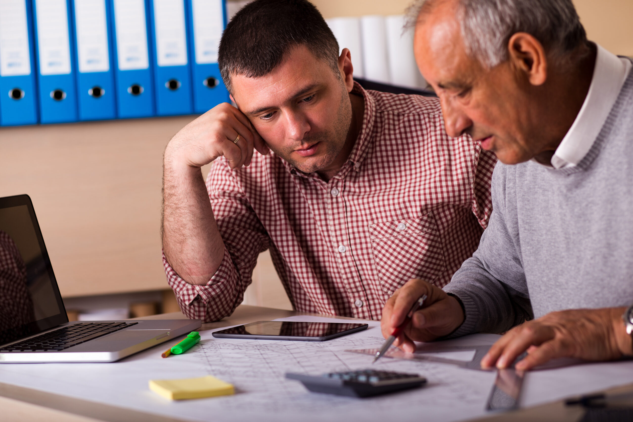 Senior and young architect working together on a project in the office, senior architect mentoring young colleague.